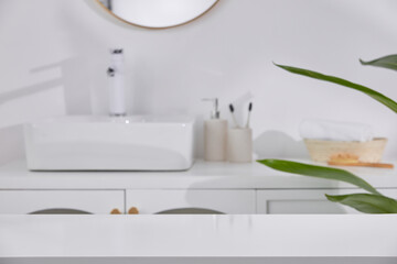 A modern bathroom with white enamel furniture, a washbasin, a cosmetic bottle, toothbrush and white table decorated with green plants. Bathroom decoration ideas. - Powered by Adobe