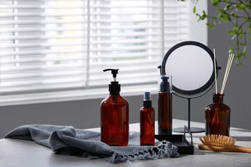 Cosmetics products, mirror, wooden comb, gray towel are display on the white table. Empty label