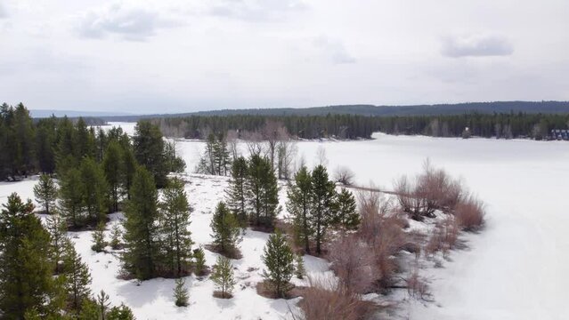Drone Aerial of the winter and the edge of the water covered in snow and showing the vacation homes around Island Park Reservoir in Island Park Idaho