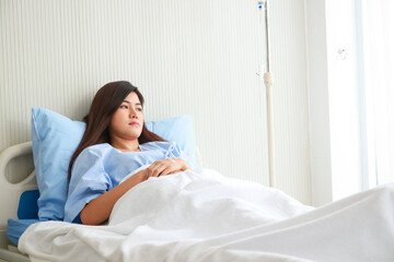 Asian female patient stressed and worried Lie on the bed in the patient room. The concept of health insurance. Hospital medical services