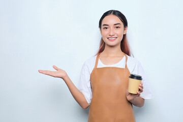 Cheerful pretty young barista girl in apron holding a takeaway cup of coffee, showing copy space on palm isolated on white background