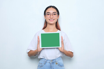 Cheerful young Asian girl in white t-shirt showing digital tablet with empty screen isolated on...