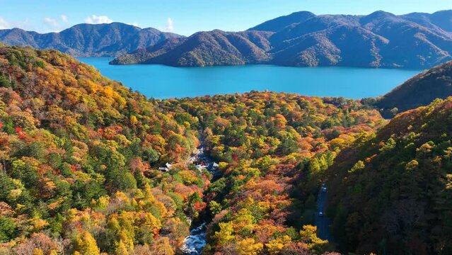 autumn at lake Chuzenji in Japan, aerial view of famous Japanese travel destination in Nikko national park, flying above autumn forest near blue lake