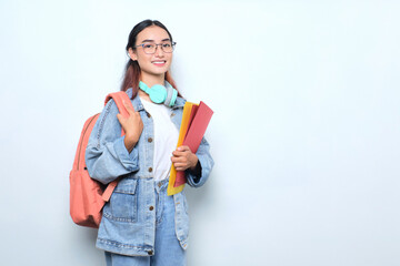 Smiling young pretty woman wearing a backpack holding books isolated on white background