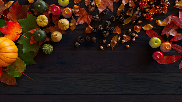 Thanksgiving Background with Fall leaves, Gourds and Acorns on a Dark wood Surface.