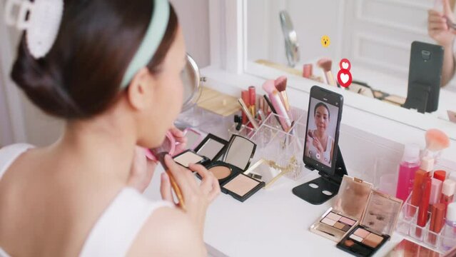 Asia Gen Z influencer youtuber girl live talk on IG instagram tiktok blog vlog. Young adult woman blogger page vlogger record video home selfie showing makeup skill fan chat hit like love emoji icon.