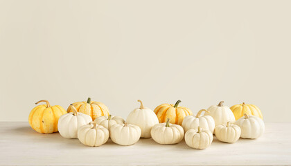 White and orange mini pumpkins on a beige background. Autumn harvest on a white table.