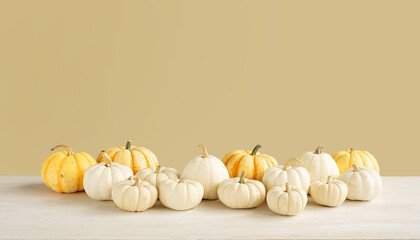 Still life of white and orange pumpkins on a wooden table on a beige background. Farmer's harvest of sweet mini pumpkins for Thanksgiving. Fall header with copy space.