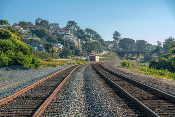 Fototapeta na wymiar Close up of a railroad with rusty tracks along cliff homes against blue sky