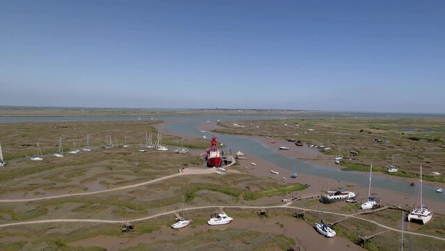 Aerial view towards a light ship stuck in mud at low tide, sunny Tollesbury, UK - approaching, drone shot