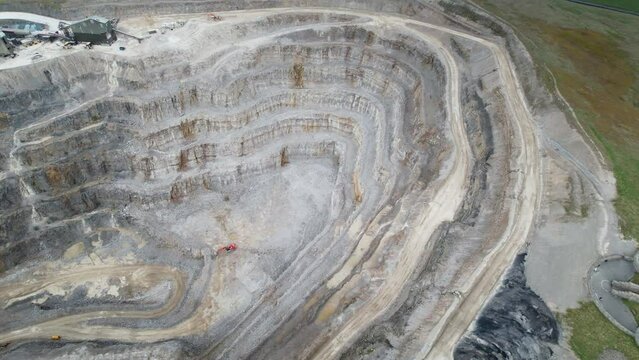 Aerial drone pan shot over green grasslands surrounding Hanson Aggregates Quarry in Harrogate, North Yorkshire, England, UK at daytime.