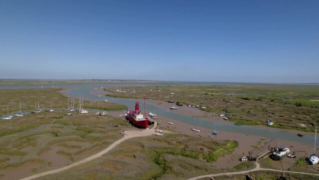 Aerial view around a Lightship stuck during the low tide, sunny Tollesbury, UK - orbit, drone shot