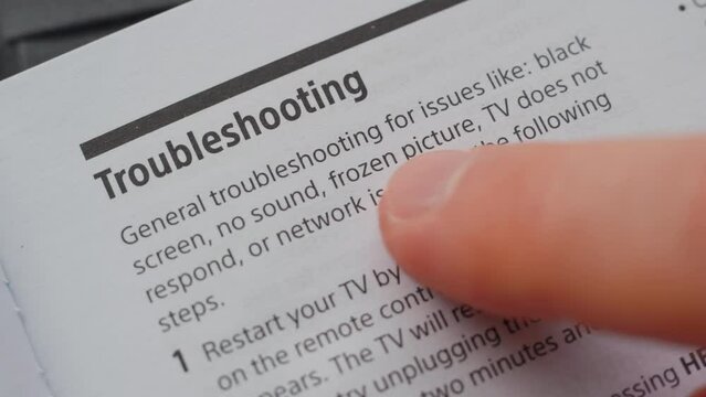 Man reading the user manual of a tv. Troubleshooting section. Extreme close up