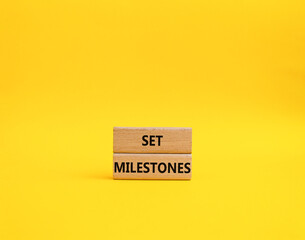 Set milestones symbol. Concept word Set milestones on wooden blocks. Beautiful yellow background. Business and Set milestones concept. Copy space