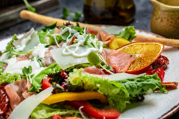 salad with pieces of smoked salmon, lettuce, sun-dried tomatoes and herbs, Healthy eating concept, tasty dinner