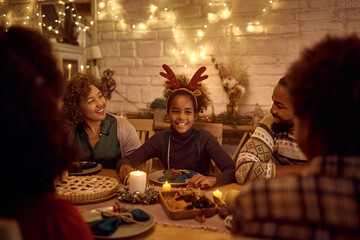 Happy African American extended family enjoys in conversation at dining table on Thanksgiving.