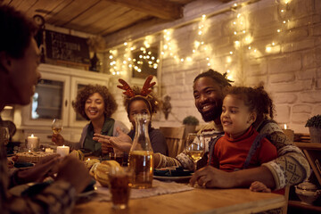 Happy black extended family talking at dining table while celebrating Thanksgiving at home,