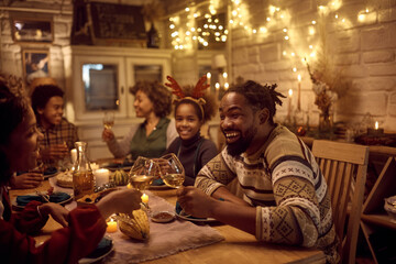 Happy black couple toasting while celebrating Thanksgiving with their family at dining table.