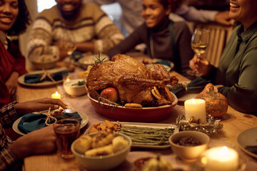 Thanksgiving turkey on dining table with extended black family in  background.