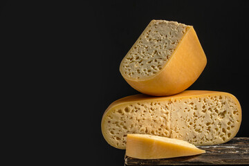 french hard cheese with holes emmentaler on a dark background. Long banner format