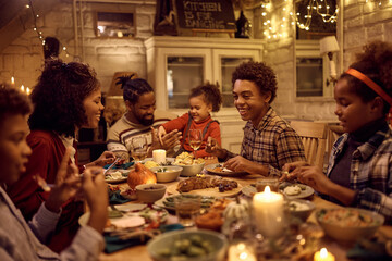 Happy black kid enjoying in family lunch for Thanksgiving at dining table.