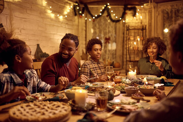 Fototapeta na wymiar Happy African American extended family talking during Thanksgiving dinner at dining table.