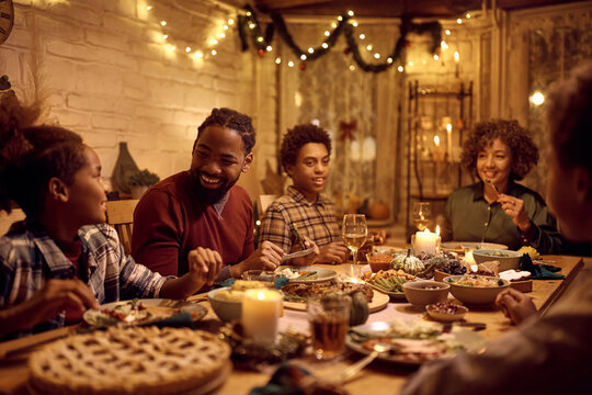 Happy African American extended family talking during Thanksgiving dinner at dining table.