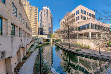 Naklejka premium River Walk in San Antonio Texas along tall buildigs with blue sky background