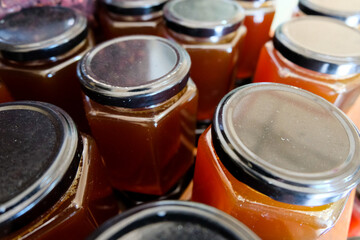 Rows of freshly made, delicious strawberry jam preserves in glass jars with screw lids, neatly lined up and ready to sale at local grocery shop