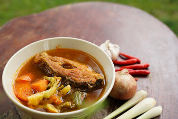 Tamarind curry with fried fish and vegetables on wooden floor - Thai style That is delicious and has been very popular.