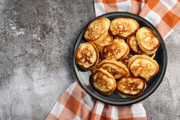 Traditional cottage cheese pancakes on a round plate on a dark grey background. Top view, flat lay