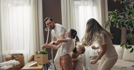 Young modern family moving in new apartment homewoners dancing with kids preschooler son and daughter having fun celebrating purchase. Delighted family concept .