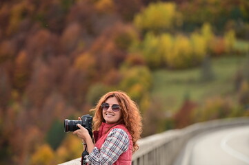Happy smiling red haired young girl with camera in hands, happy photographer.