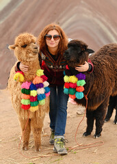 Young red haired girl with two cute alpacas at Vinicunca Rainbow Mountain, Peru