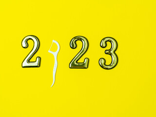 2023 and dental concept. Close up view photo with 2023 and white dental floss stick instead zero on yellow background with copy space. Christmas medical card. Merry Christmas and Happy New Year