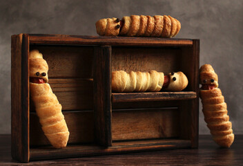 sausage in the dough in the form of a mummy in a wooden box for the Halloween holiday