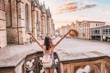 Happy woman tourist with backpack enjoying panorama of the city hall rathaus and market square of...