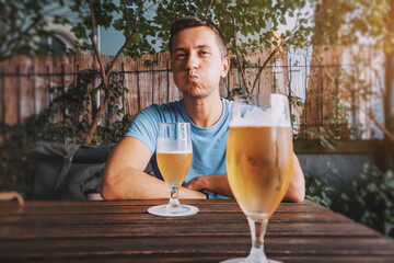 Funny drunk man drinks freshly brewed light beer from glasses in a bar or pub or a German beer...