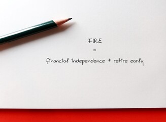 Pencil writing on paper FIRE = FIRE stands for financial independence + retire early , means   aggressive saving and prudent investing or short-term sacrifices for long-term goals