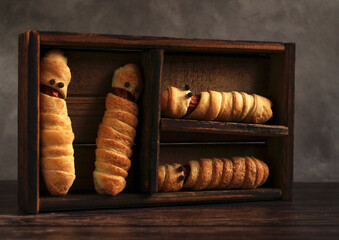 sausage in the dough in the form of a mummy in a wooden box for the Halloween holiday