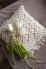 White pillows with macrame. Bed in a minimal bedroom scandinavian style. White tulip on macrame pillow