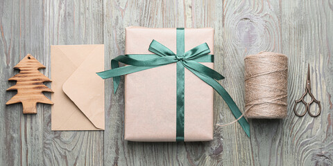 Beautiful gift box for Christmas with envelope, thread and scissors on wooden background