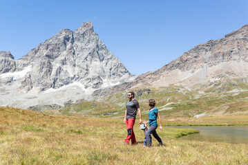 Fototapeta na wymiar Couple with her little daughter doing a hike trail around Matterhorn in Cervinia, Italy. 