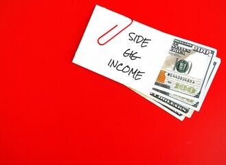 On red copy space background, dollars cash money with handwritten text note SIDE GIG INCOME,...