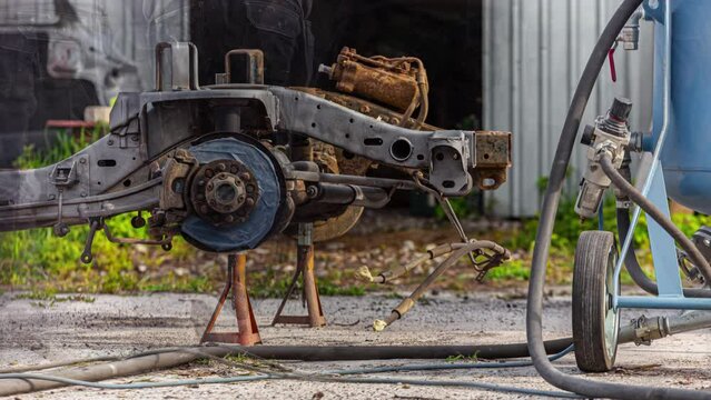 Time-Lapse of person sandblasting a axle of a truck 