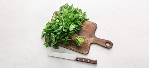 Cutting board with fresh parsley and knife on light background, top view
