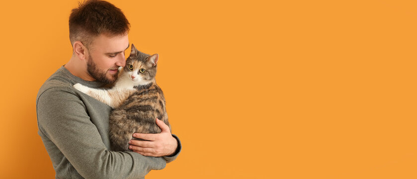 Young man and cute cat on orange background with space for text