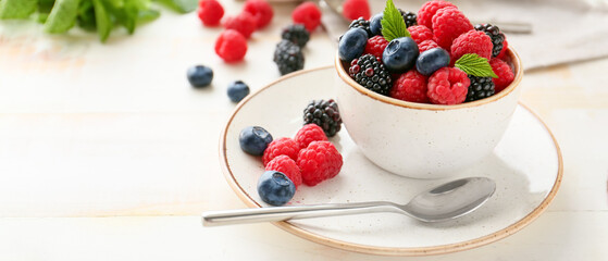 Cup with tasty ripe berries on table