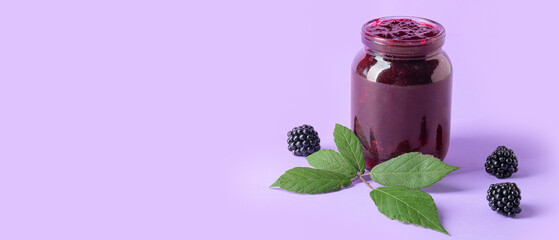 Jar of tasty blackberry jam on lilac background with space for text