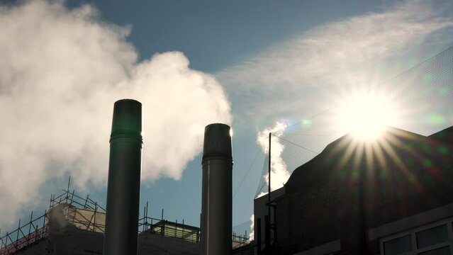 Exhaust Steam Being Expelled From Metal Flue In Morning Sunrise Against Blue Skies. Slow Motion
